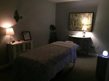 Serene massage room with a bed, soft lighting, and calming decor.